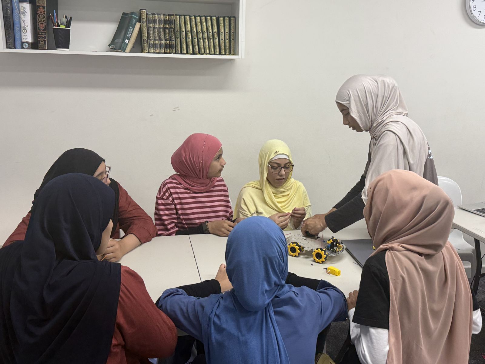 Students building small four-wheel robots around a table
